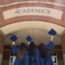 Tres mujeres con toga y birrete frente a la universidad