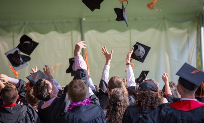 estudiantes lanzando birretes al aire